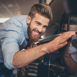 Happy man inspecting car at car dealership