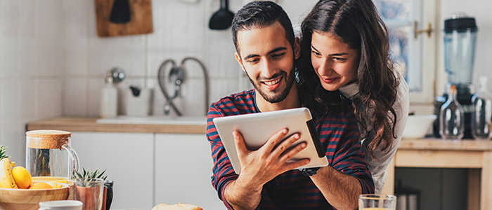 A couple uses a tablet to research homes for sale.